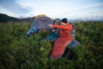 duas pessoas a ver a paisagem perto da sua tenda de campismo