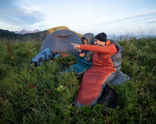 duas pessoas a ver a paisagem perto da sua tenda de campismo