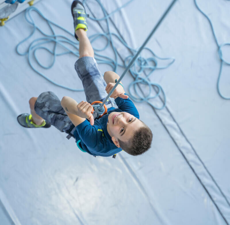 Un petit garçon souriant en pleine pratique de l'escalade à l'intérieur