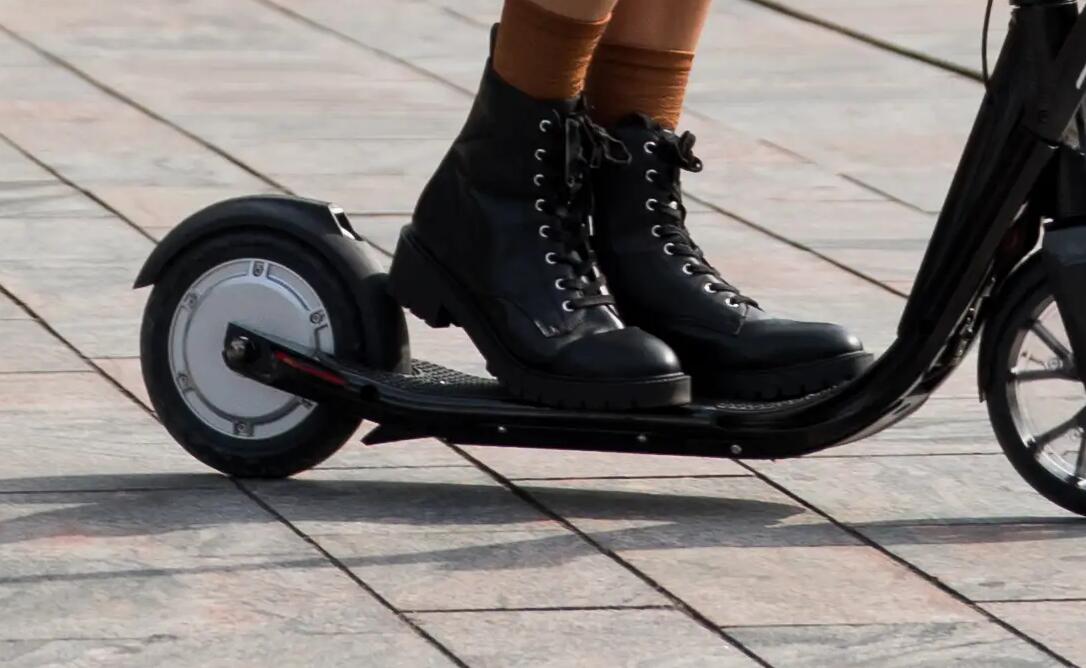 Pessoa a andar numa trotinete e a utilizar o travão de pé