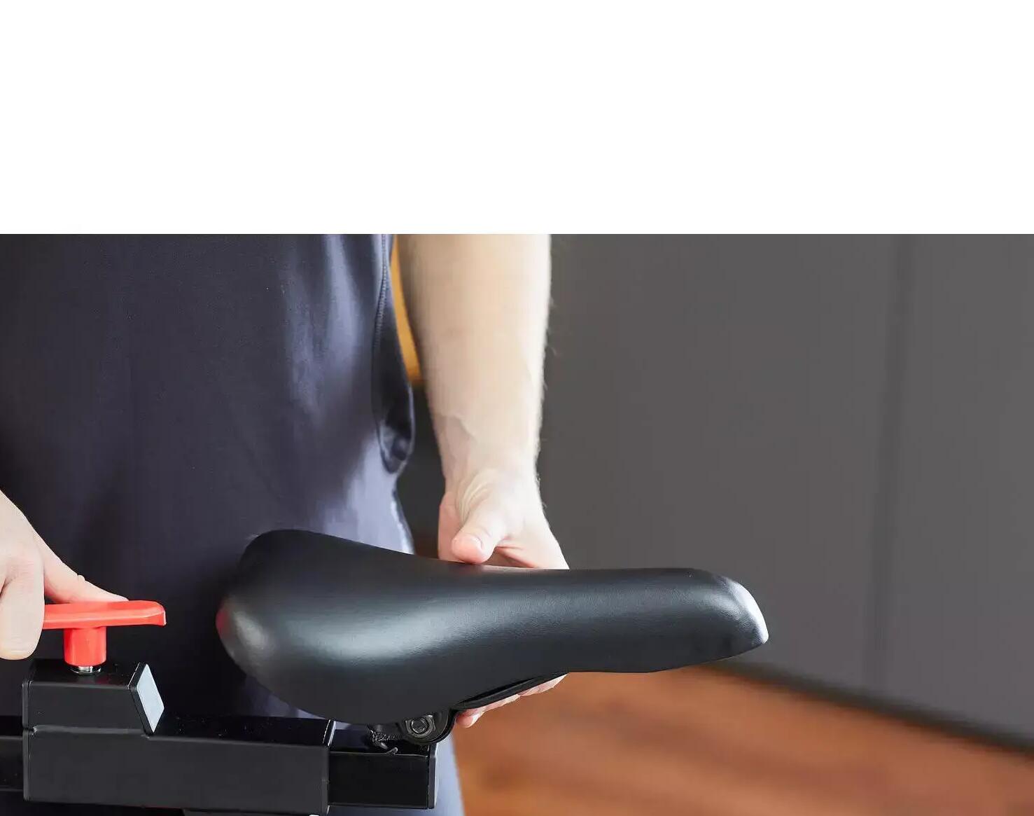 mulher a ajustar o selim de uma bicicleta de spinning domyos