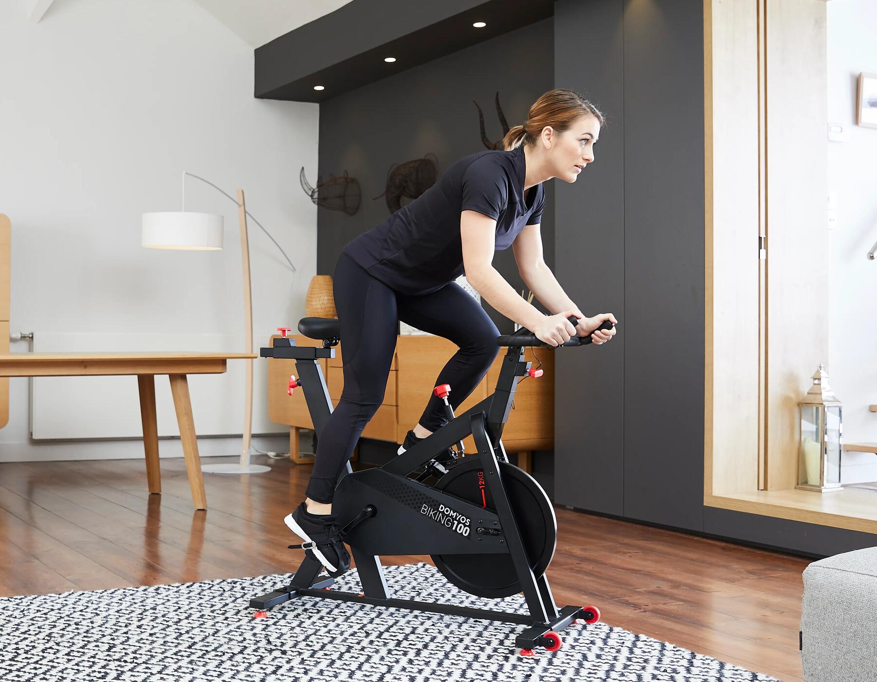 mulher a pedalar em pé intensivamente na bicicleta de spinning domyos biking 100