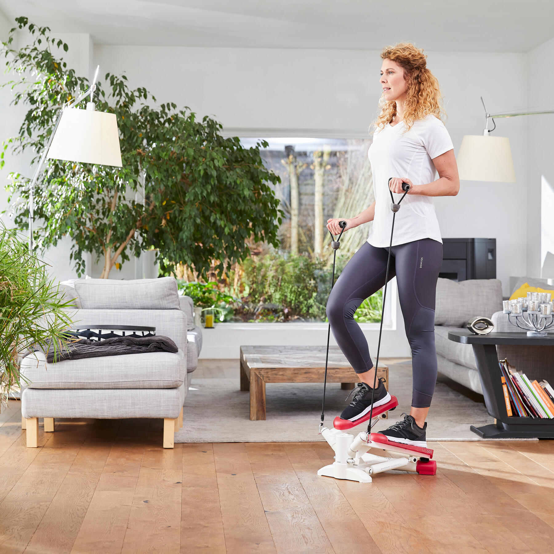 senhora a fazer exercício num mini stepper 500 com elásticos