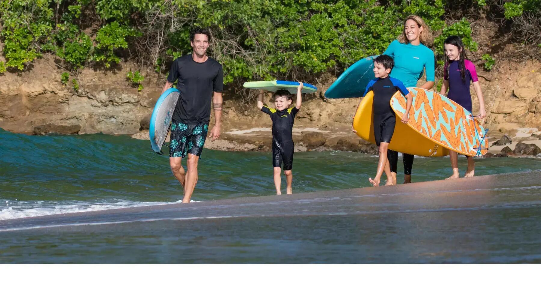 crianças e pais com pranchas de surf junto ao mar