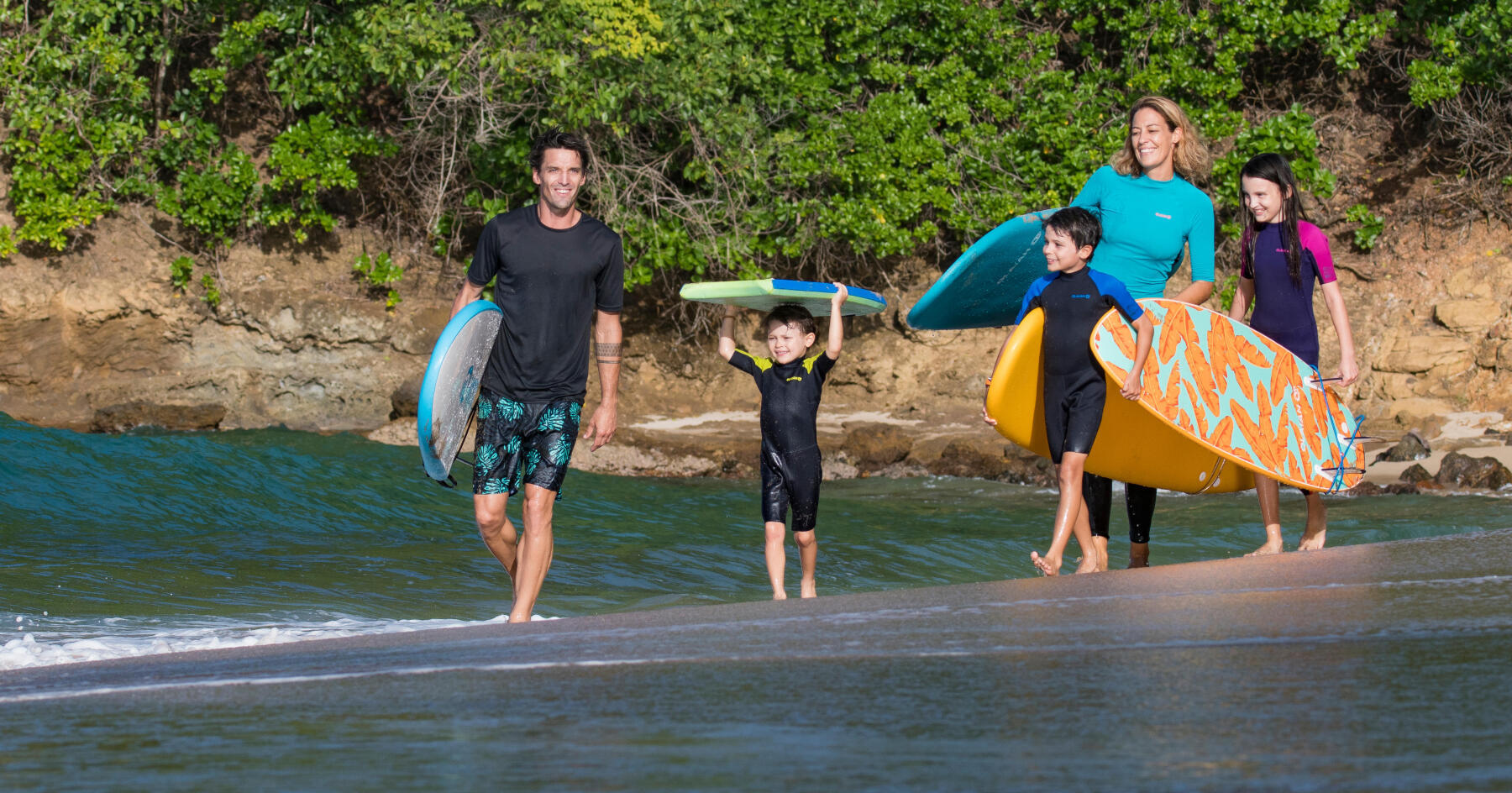 crianças e pais com pranchas de surf junto ao mar