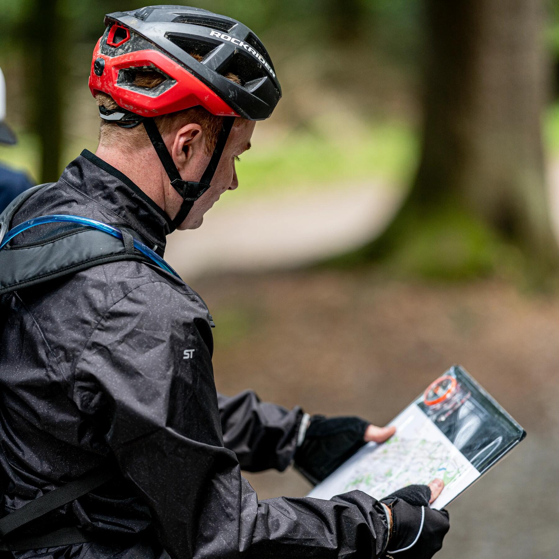 Mężczyzna robiący przerwę podczas górskiej przejażdżki rowerowej aby sprawdzić na mapie gdzie jest