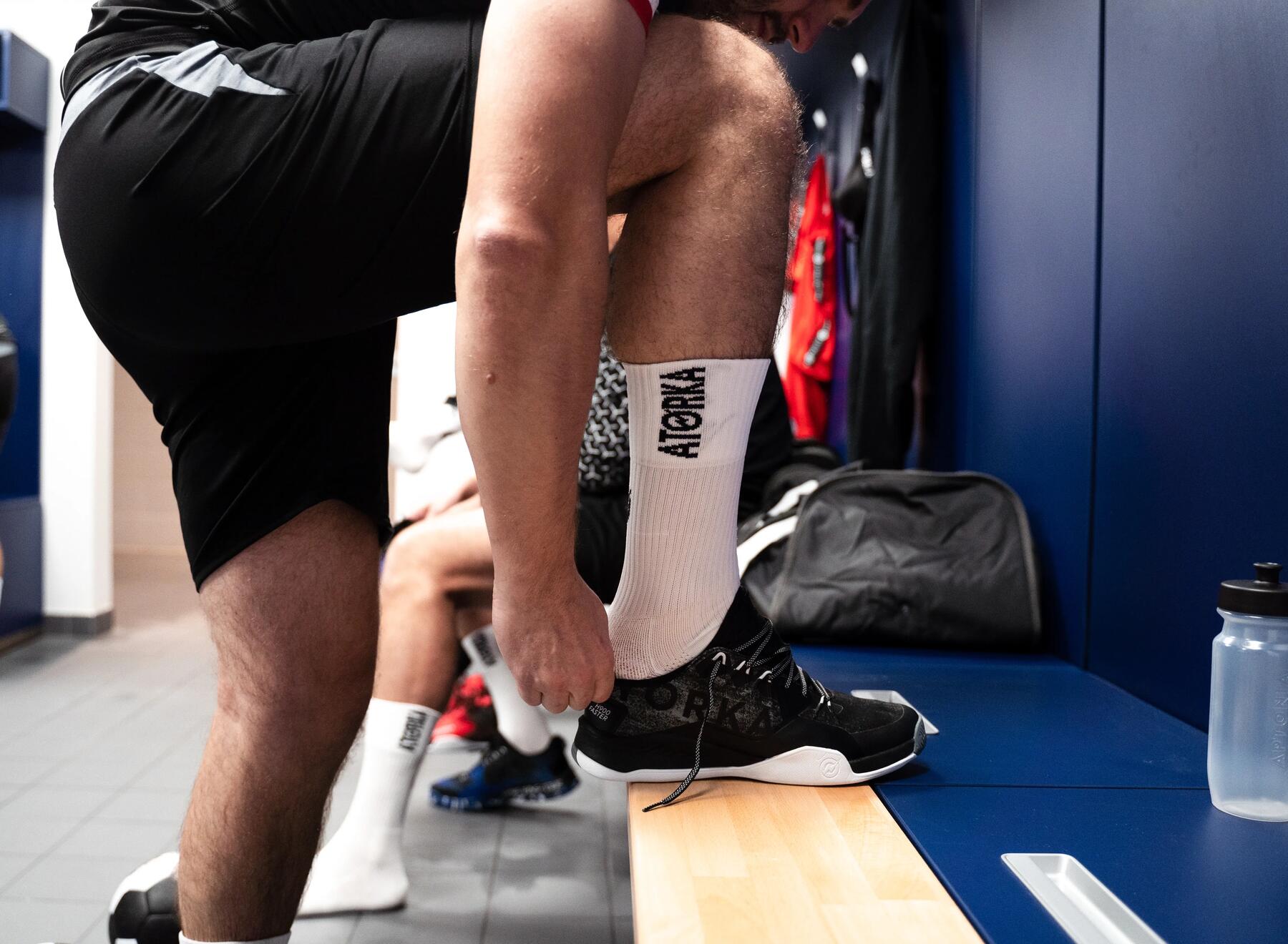 Mann zieht sich seine Handballschuhe von der Marke Atorka an