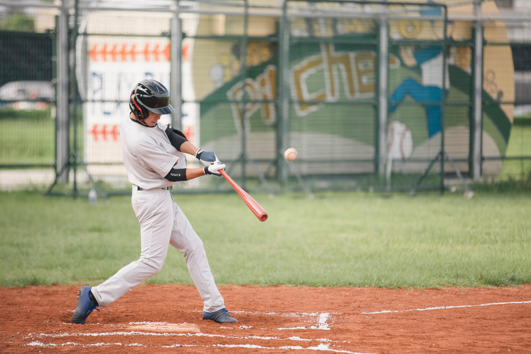 Zawodnik odbijający piłkę baseballową kijem do baseballa stojąc na boisku