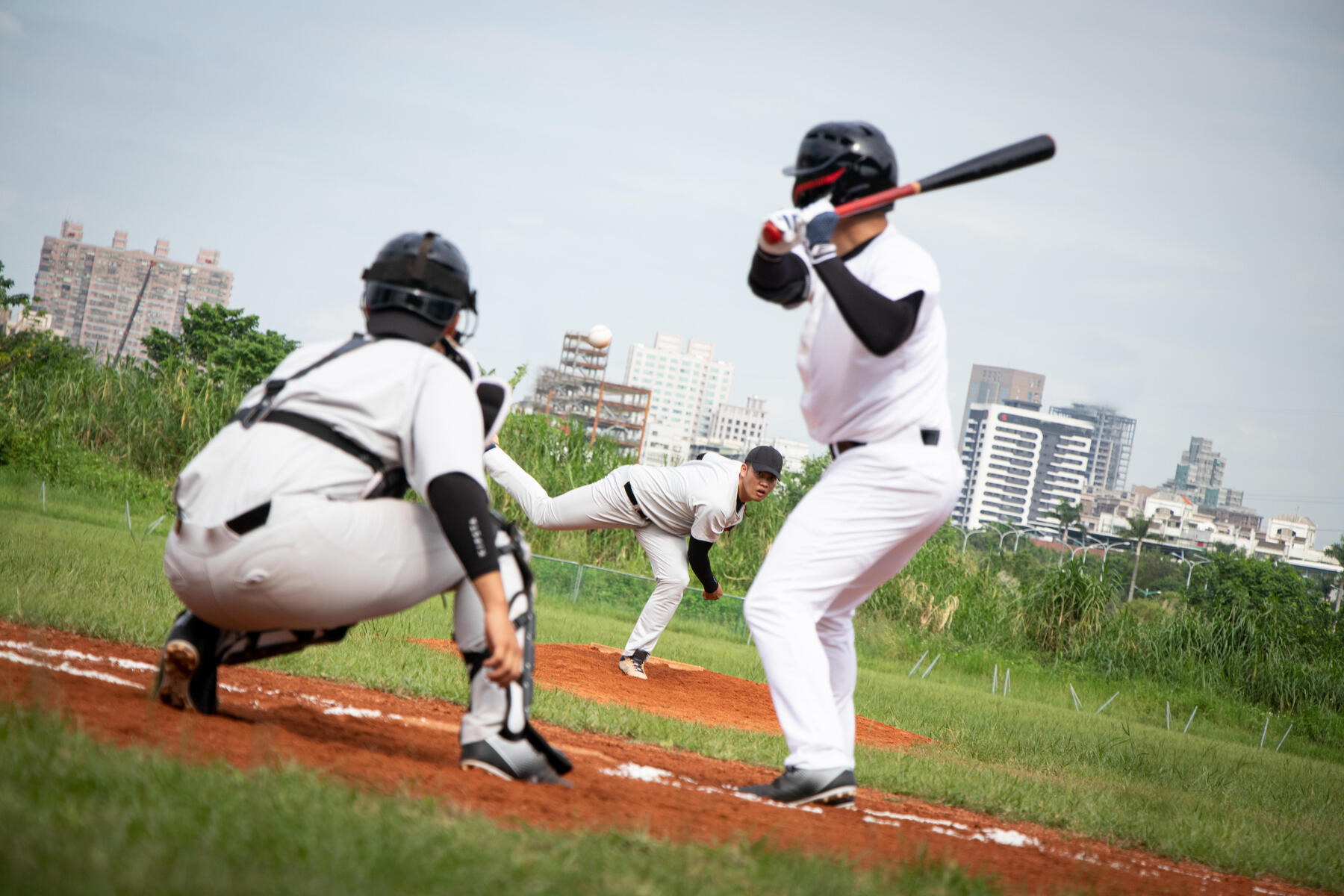 Zawodnicy w kaskach i strojach baseballowych grający mecz baseballa na boisku