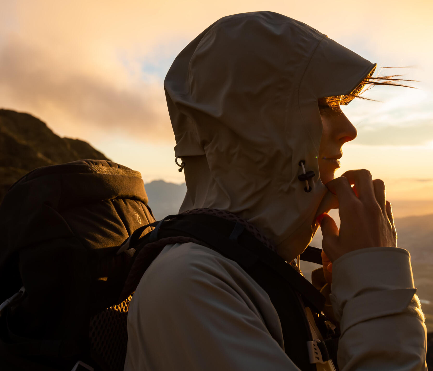 Une femme en randonnée au top d'un sommet regardant le couché de soleil