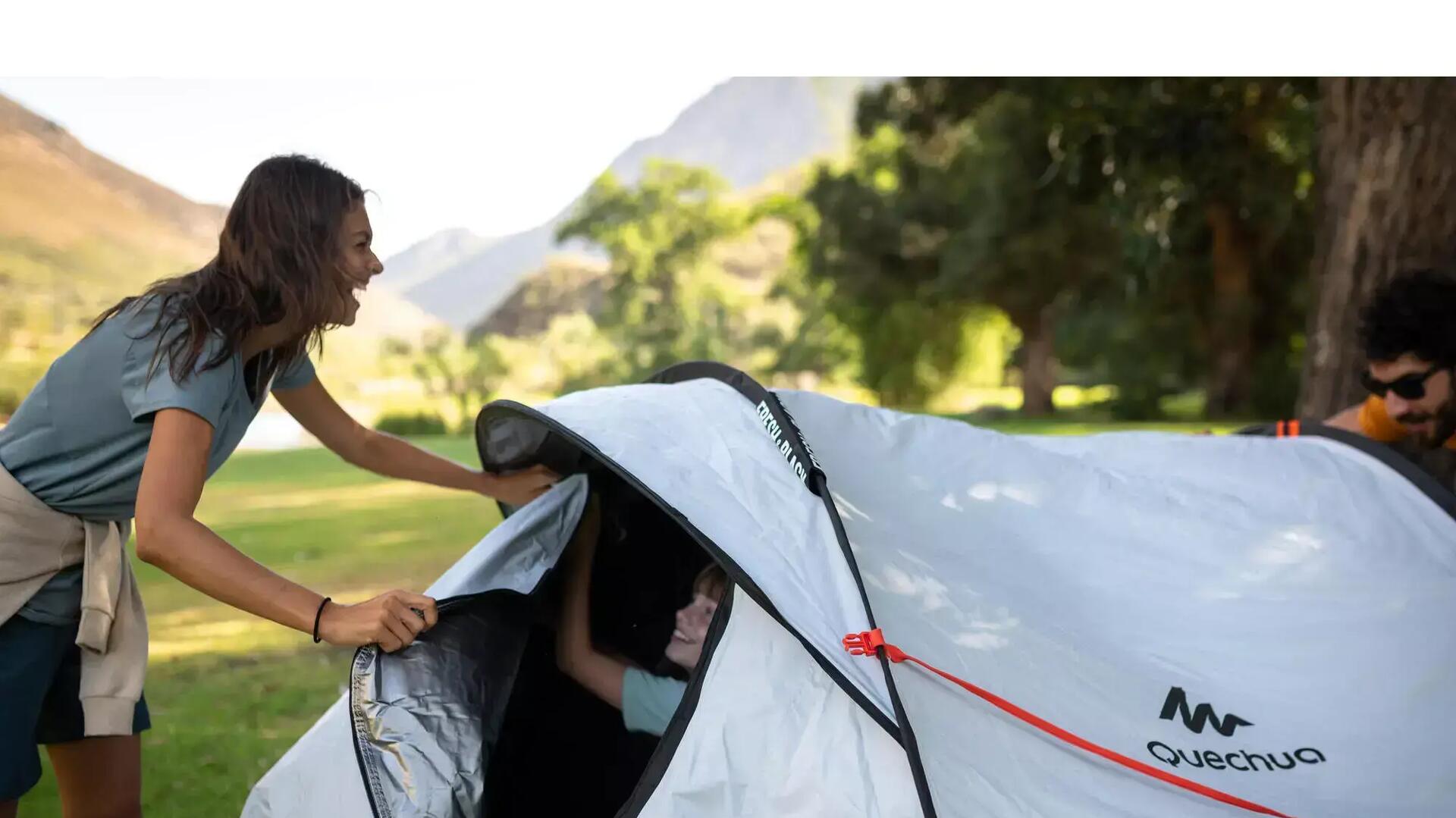 A smiling mother and son close their tent