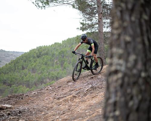 mężczyzna zjeżdżający rowerem MTB z góry w odzieży rowerowej 