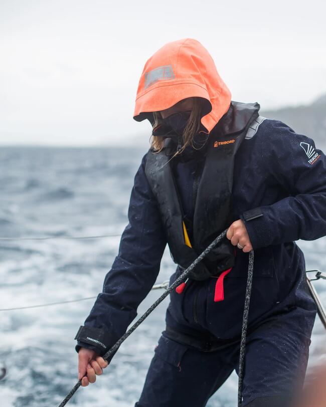 Vrouw met automatisch reddingsvest aan bestuurt de zeilboot