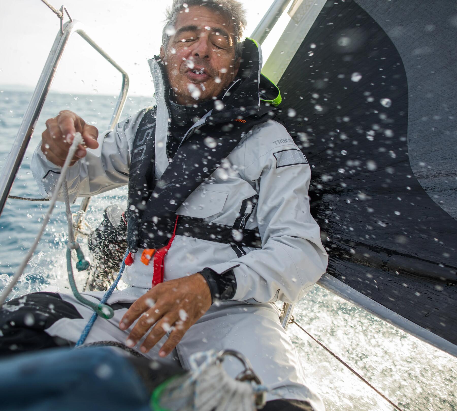 Man wearing life jacket getting splashed by water while on boat