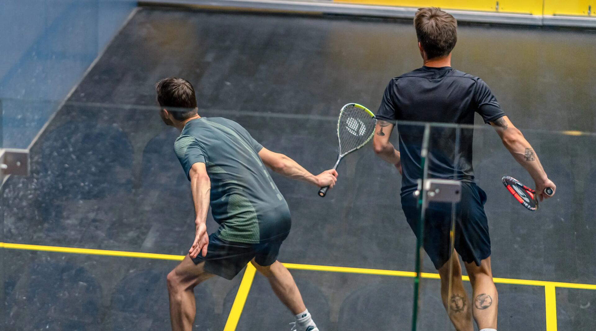 mężczyźni w odzieży do squasha grający w squasha na korcie