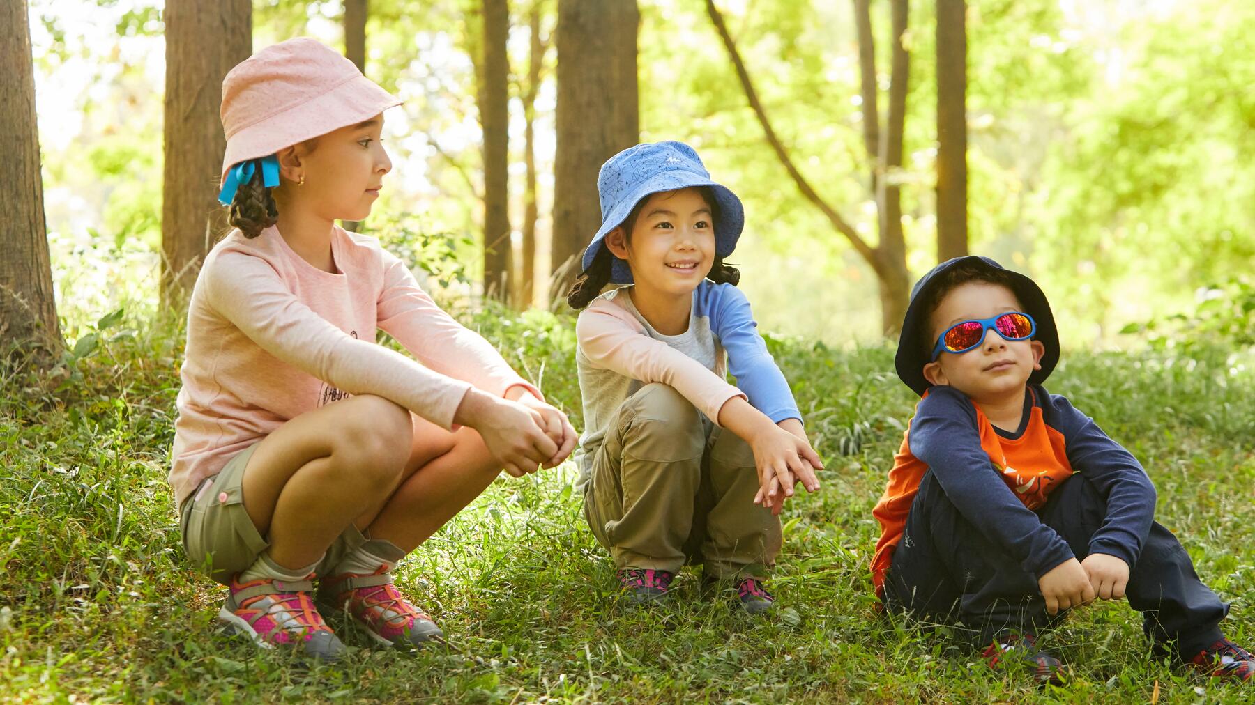 Drei Kinder sitzen im Wald und geocachen