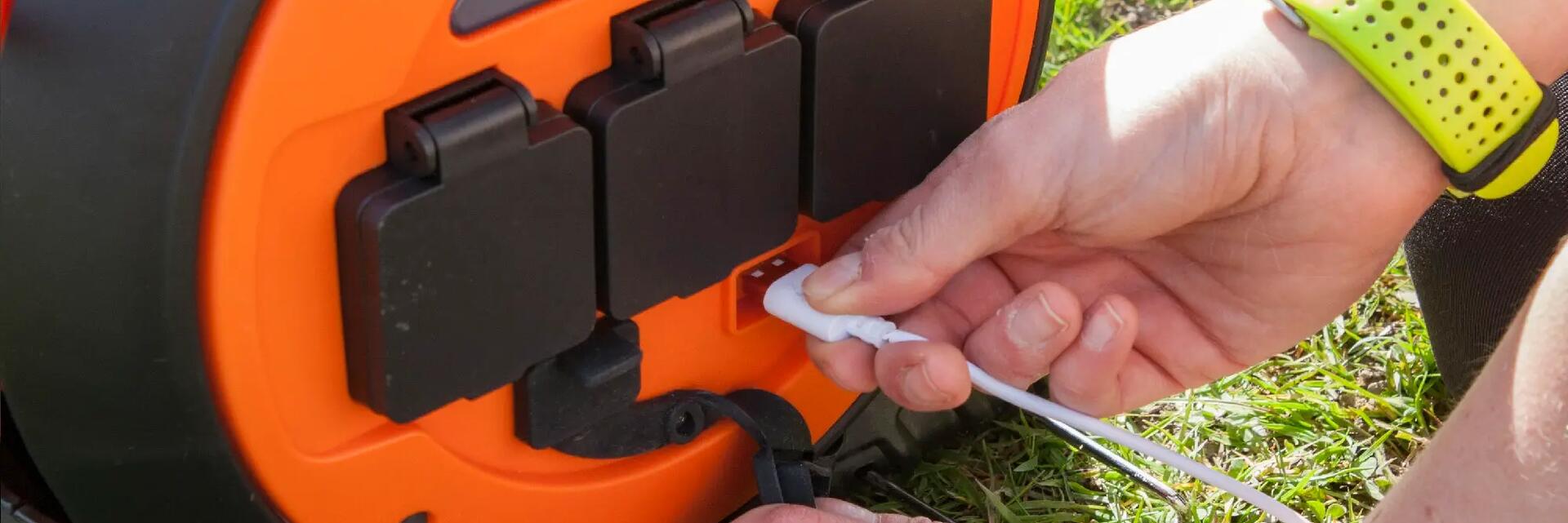 Mężczyzna podłączający kabel do przedłużacza bębnowego