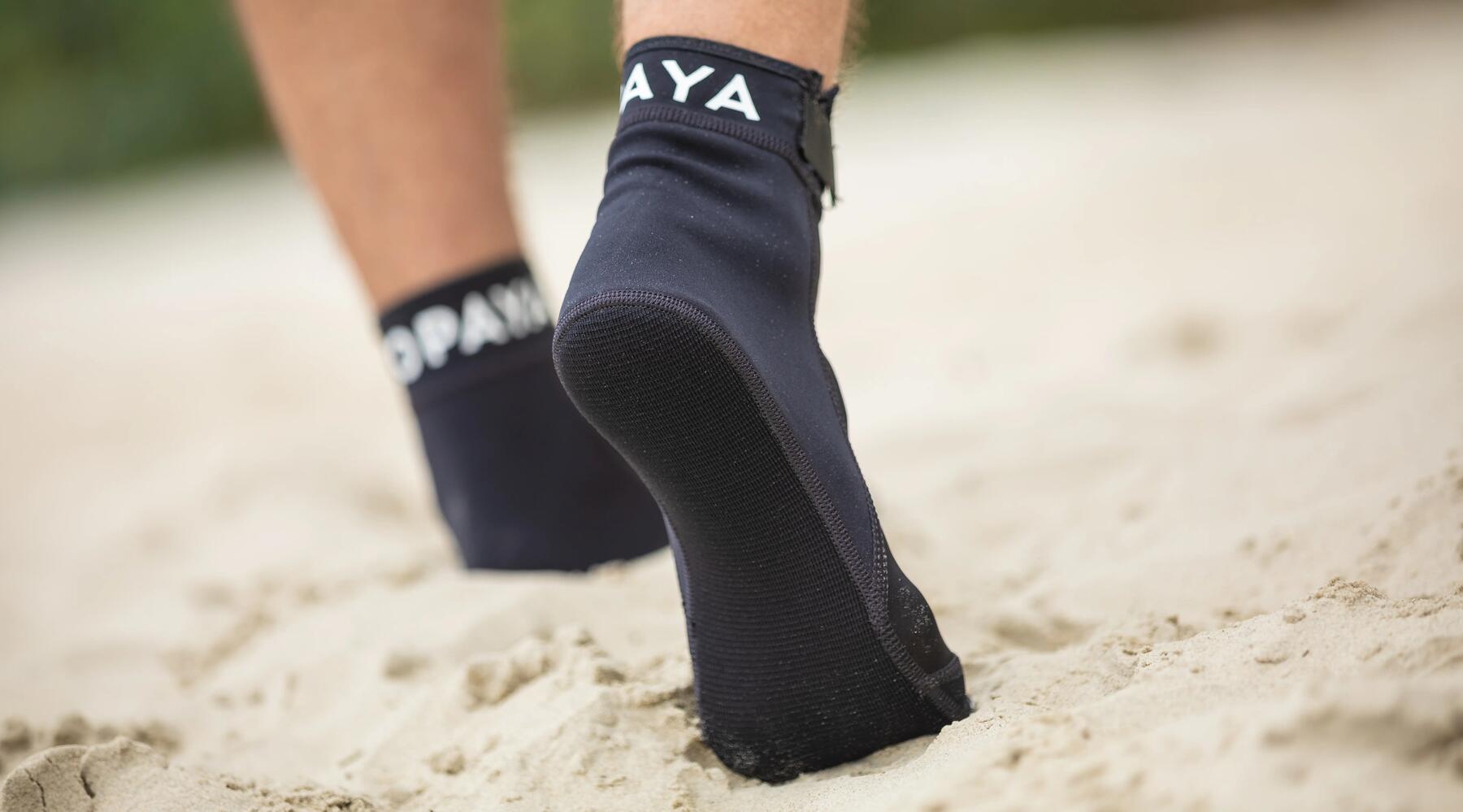 Bild von einer Person, die mit Neoprensocken auf Sand läuft