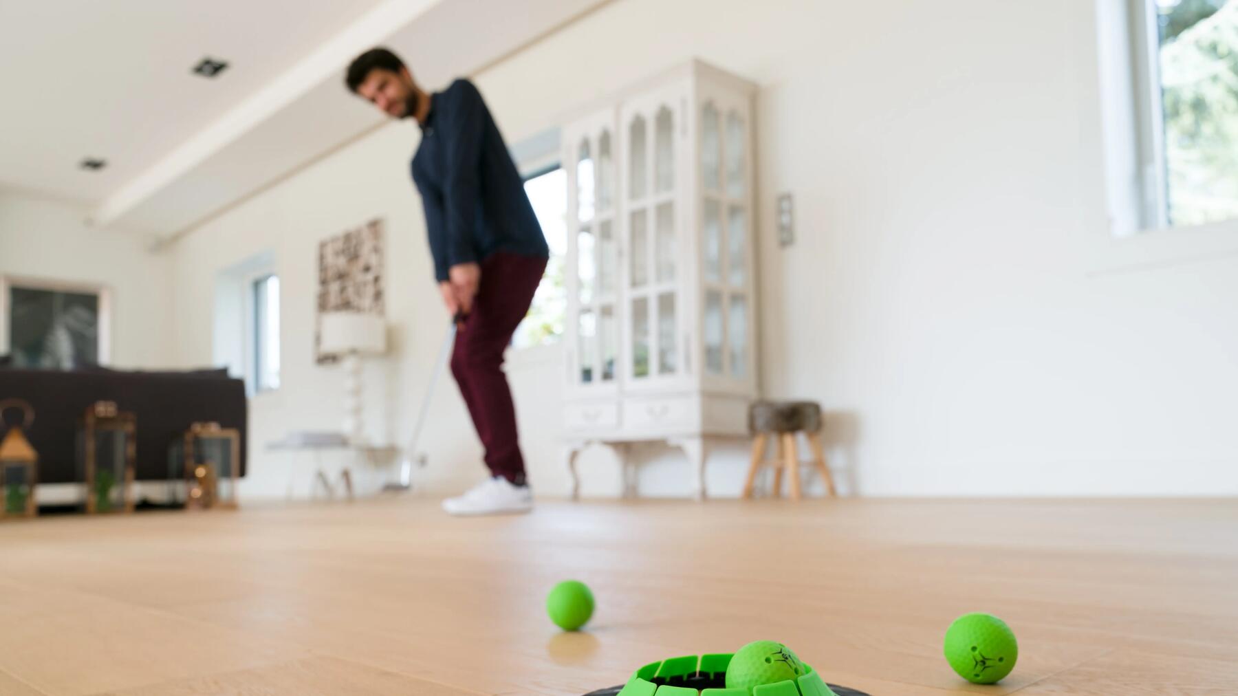 jovem a jogar com putting de golf em casa