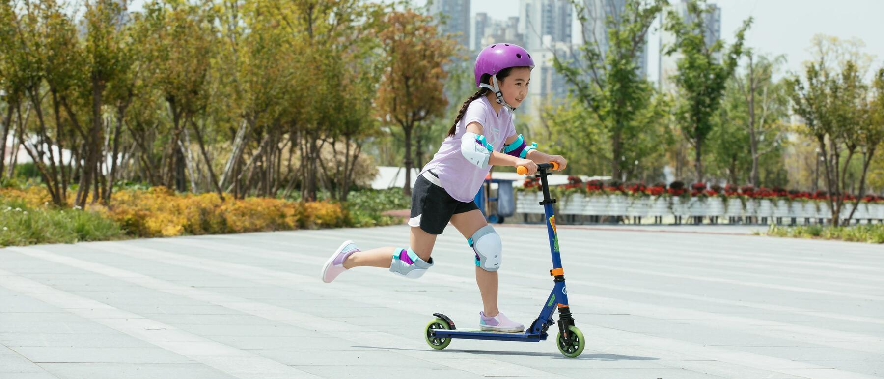 Kind fährt auf einem Roller mit Schutzausrüstung