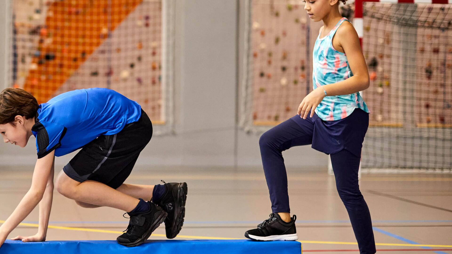 dziewczynka i chłopiec w odzieży gimnastycznej ćwiczący na sali treningowej