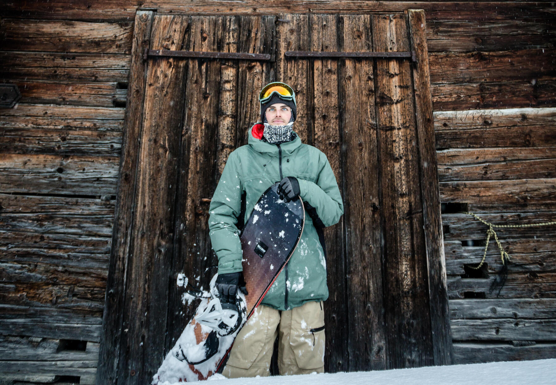 Man standing in front of cabin with his snowboard