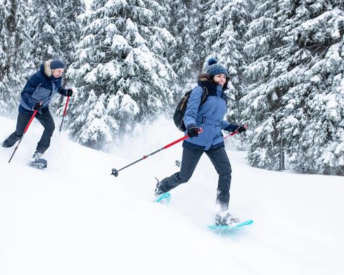 man and woman snowshoeing in the forest