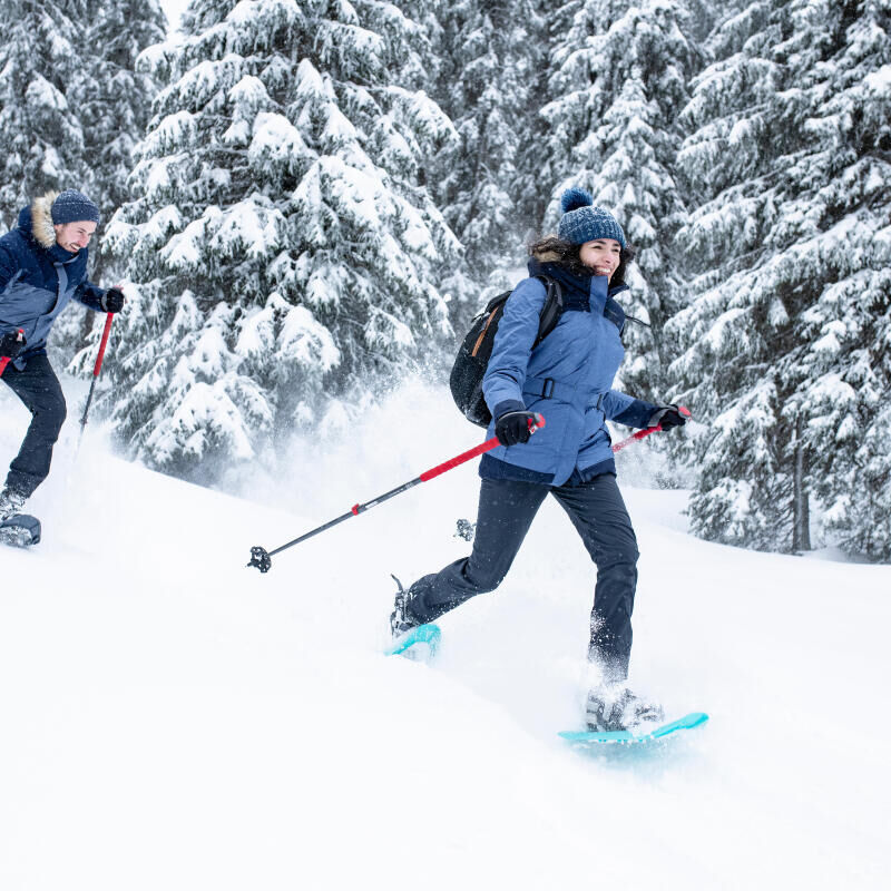 man and woman snowshoeing in the forest
