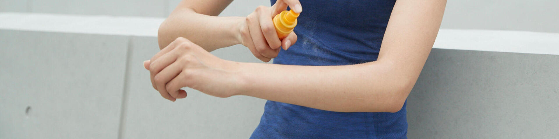 woman putting sunscreen on her arm