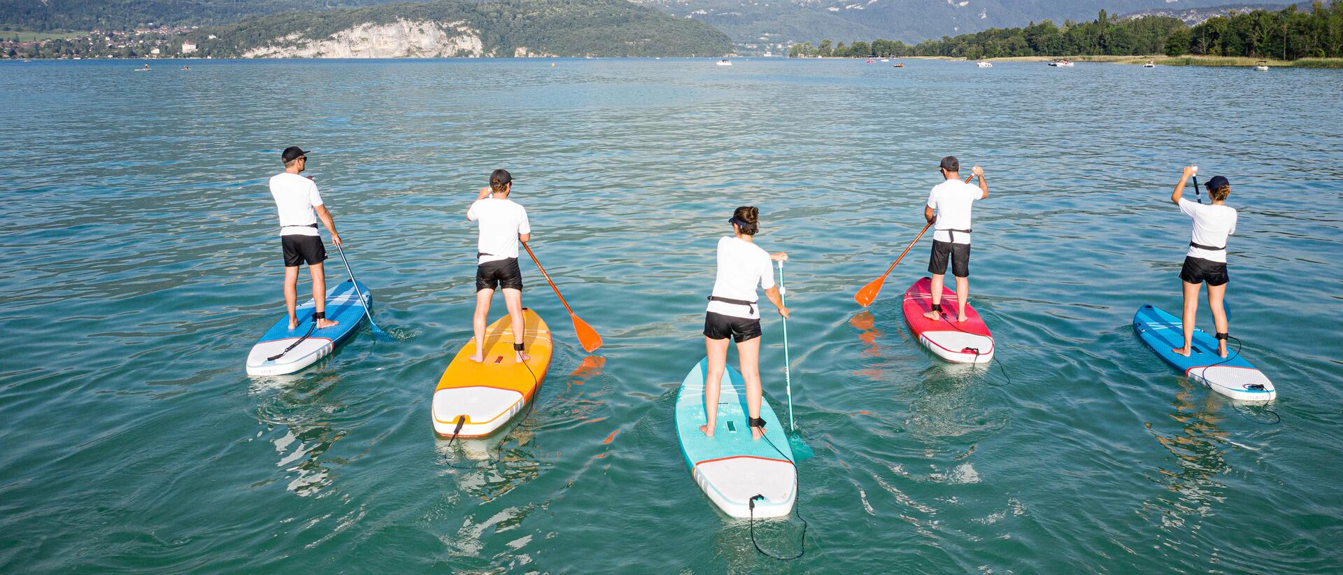 A group of people paddling on Stand up paddle boards of different colors.