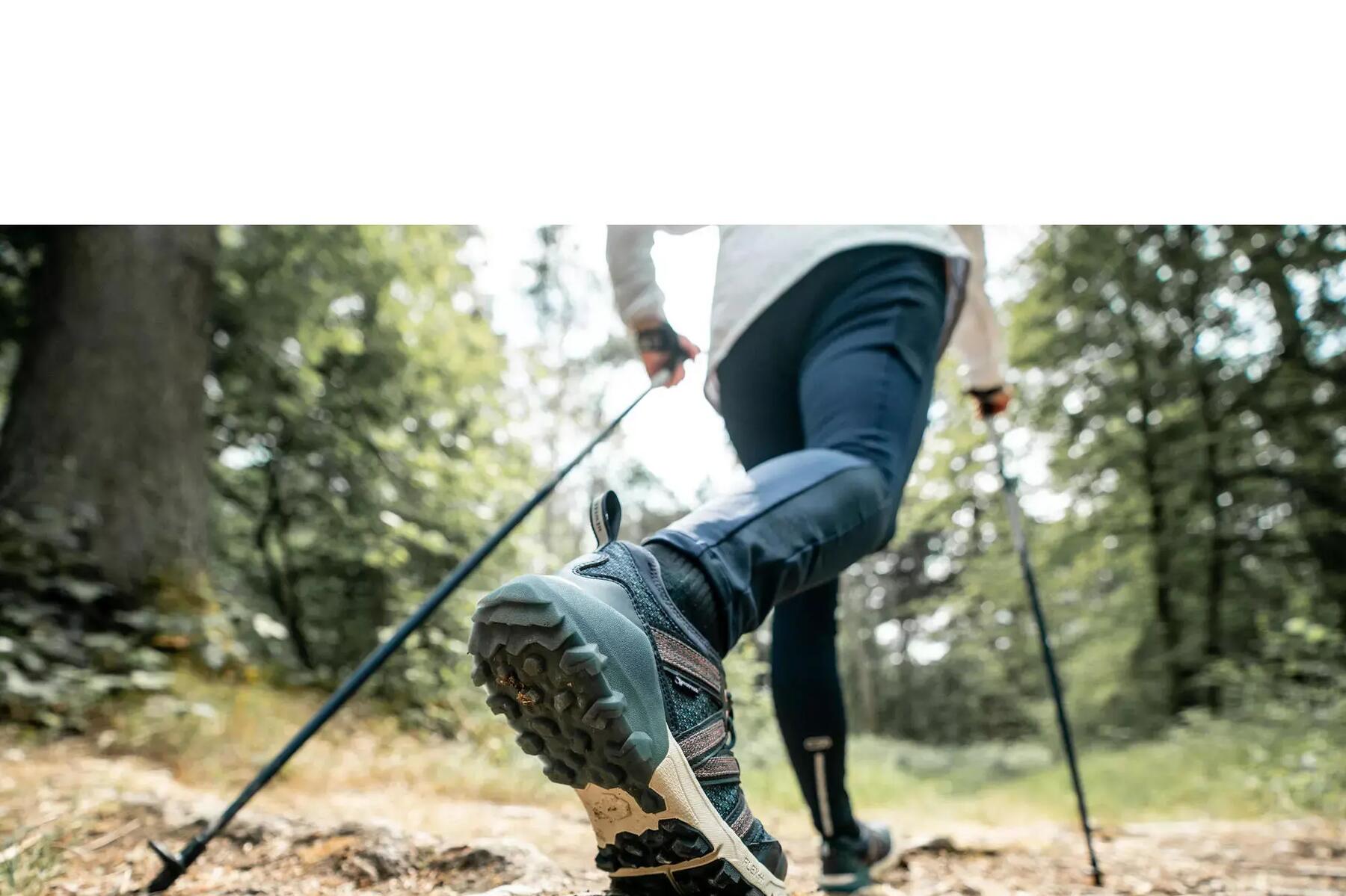 Nahaufnahme von Wanderschuhen und -stöcken eines Wanderers im Wald