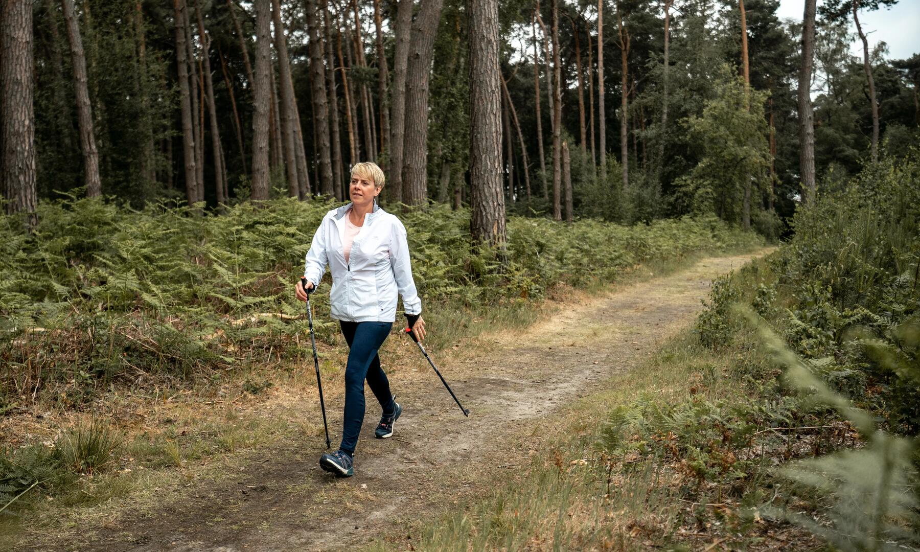 Frau wandert mit Walking-Stöcken im Wald