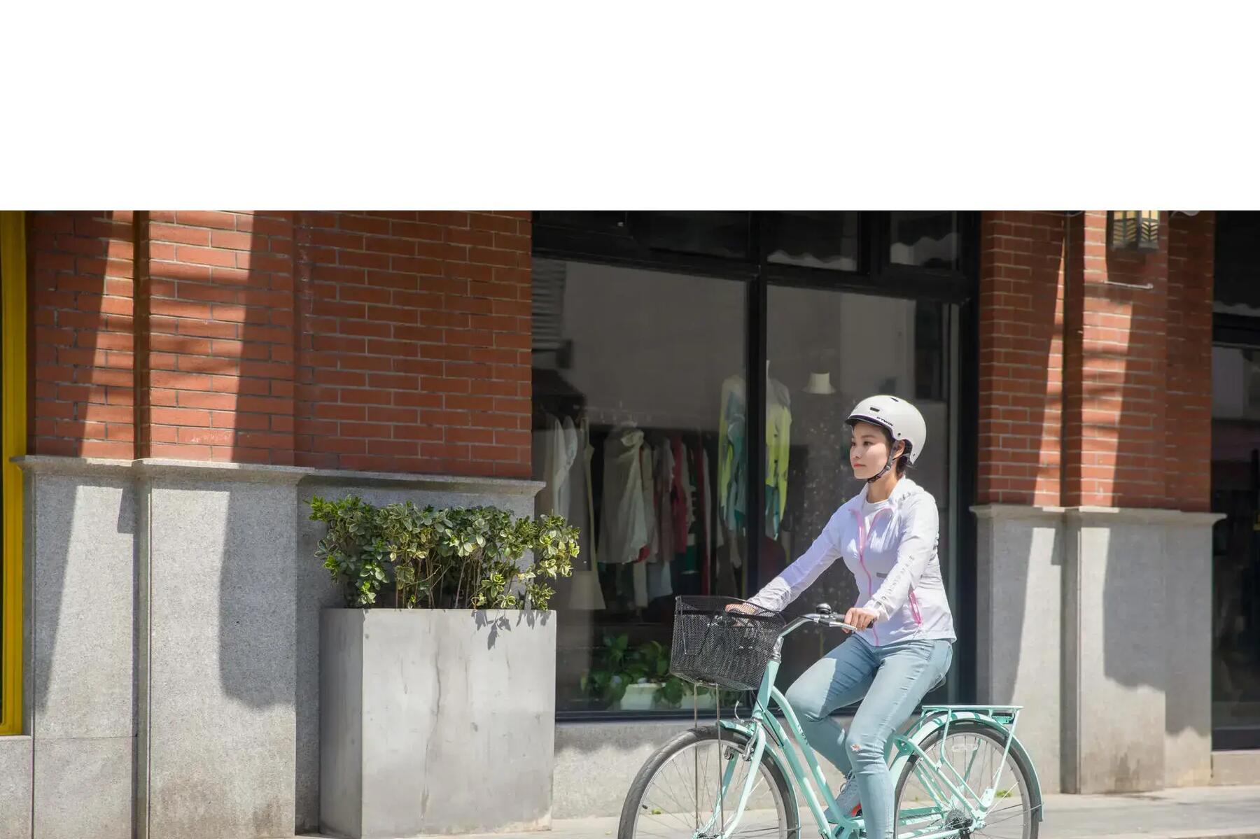 Kobieta jadąca na rowerze miejskim z oponami zwijanymi ubrana w kask ochronny