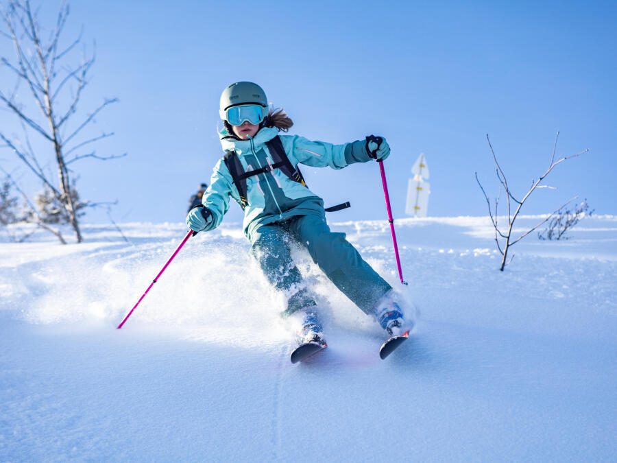 En flicka som åker skidor i en slalombacke