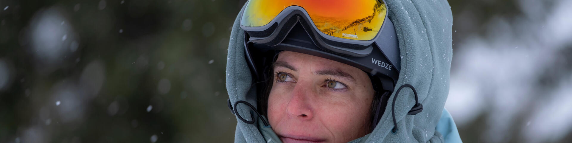 Une femme qui regarde la pente de ski avec ses lunettes sur la tête