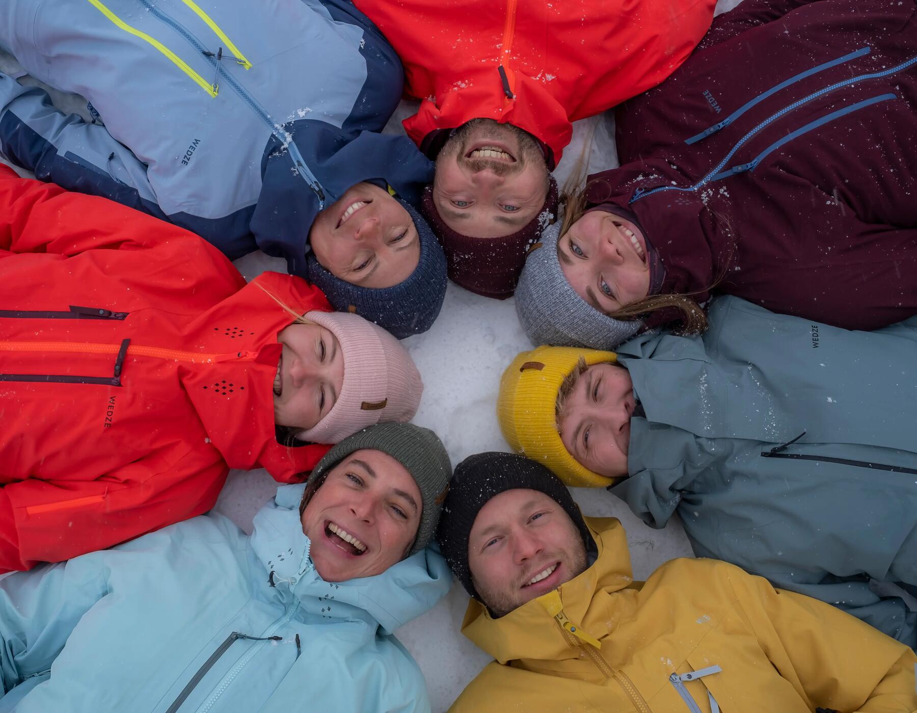 People laying on snow, in circle, smiling