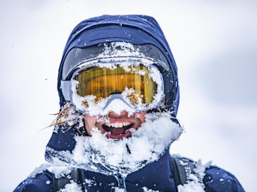  A man with a face full of snow protected by ski goggles