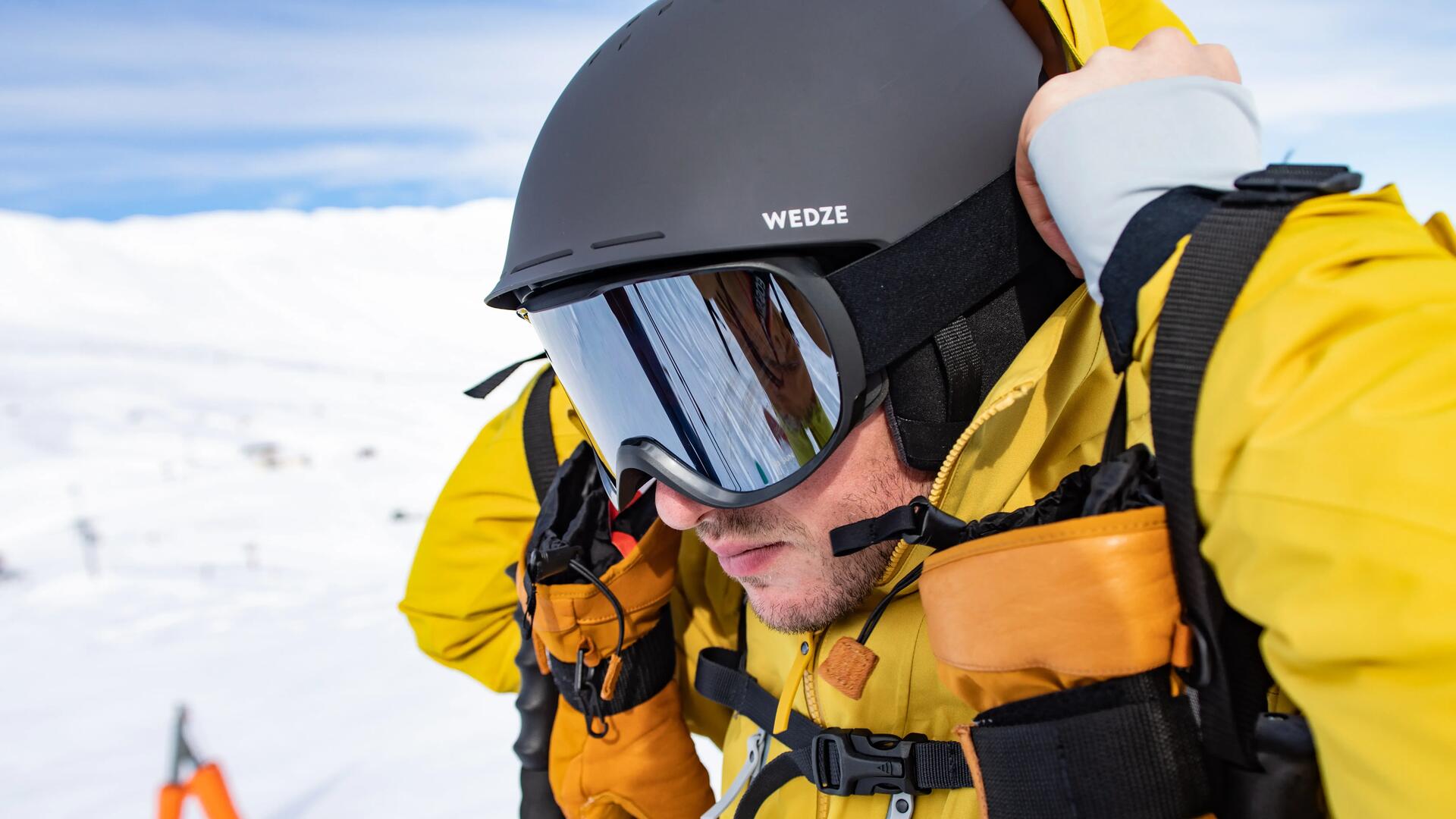 Closeup of a man putting his ski goggles on.