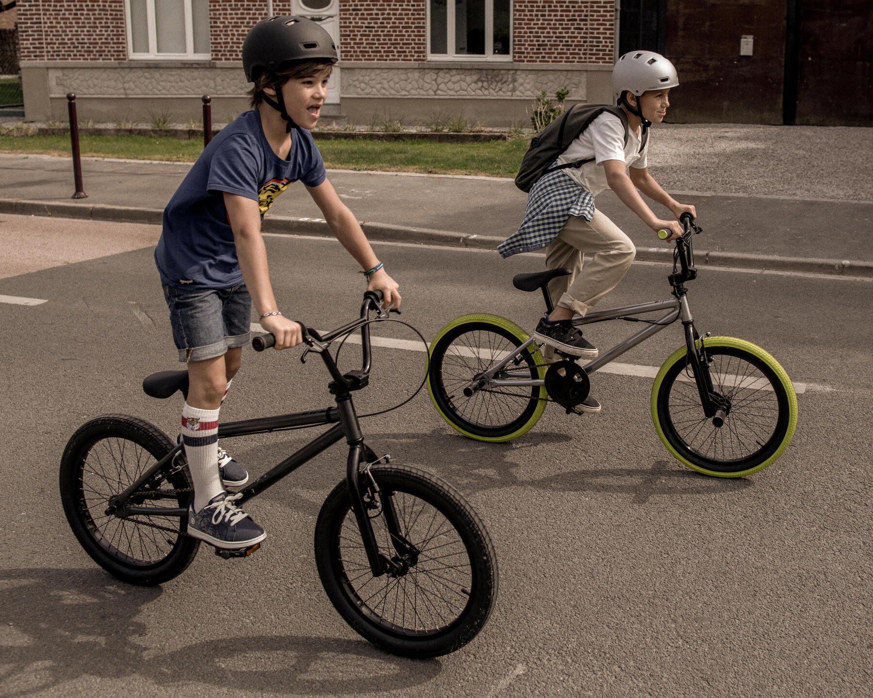 Två barn åker på BMX-cyklar, en står upp isadeln.