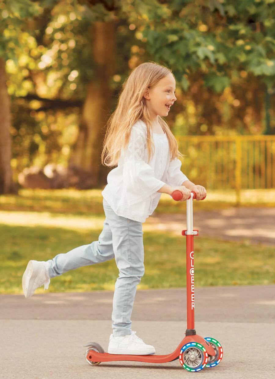 Kleines Mädchen fährt auf einem Roller mit drei Rädern