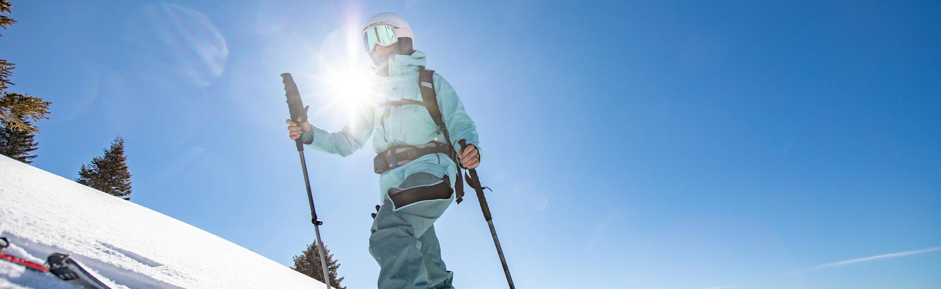 osoba w odzieży narciarskiej trzymająca kijki narciarskie na stoku