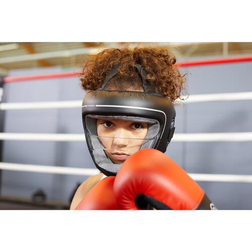 A boxer wearing red gloves and her head guard