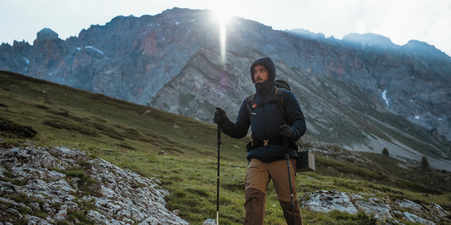 mężczyzna z plecakiem turystycznym na plecach wędrujący po górach z kijkami trekkingowymi