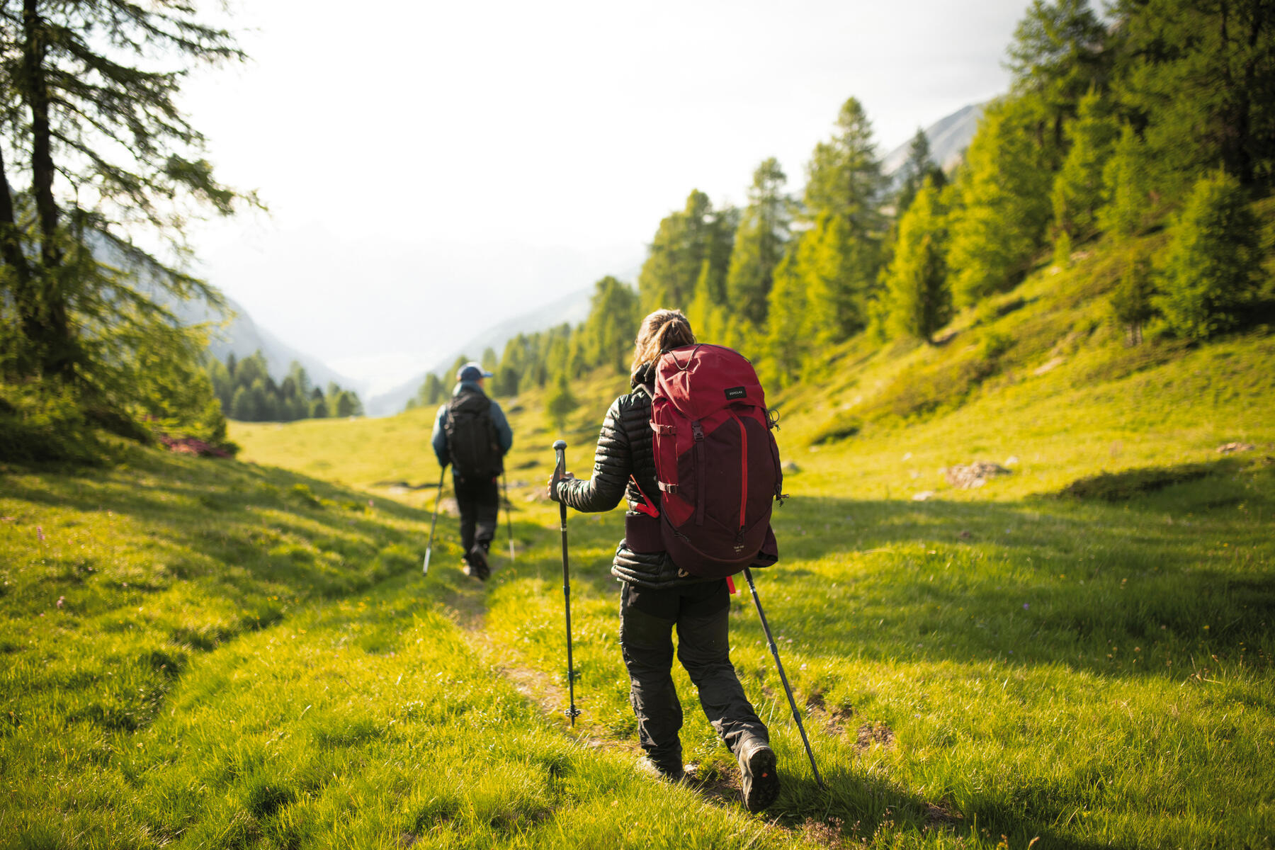 Dwoje ludzi z plecakami wędrujący po górach z kijkami w rękach