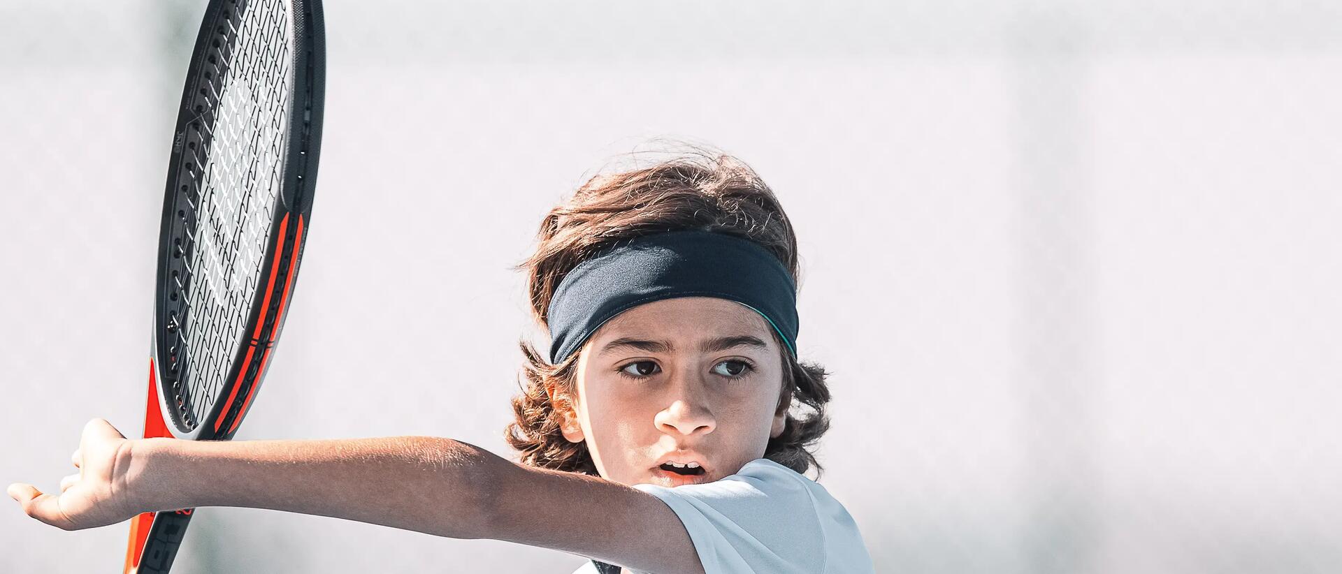chłopiec z opaską na głowie trzymający rakietę do tenisa ziemnego w dłoni