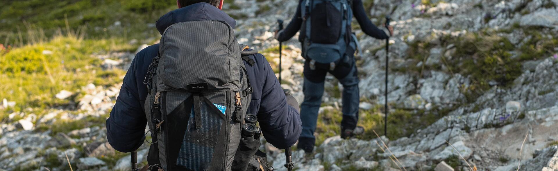 kobieta i mężczyzna wędrujący po górach z kijkami trekkingowymi i plecakami turystycznymi na plecach