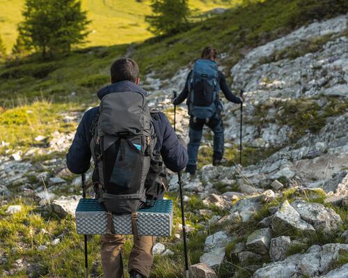 kobieta i mężczyzna wędrujący po górach z kijkami trekkingowymi i plecakami turystycznymi na plecach