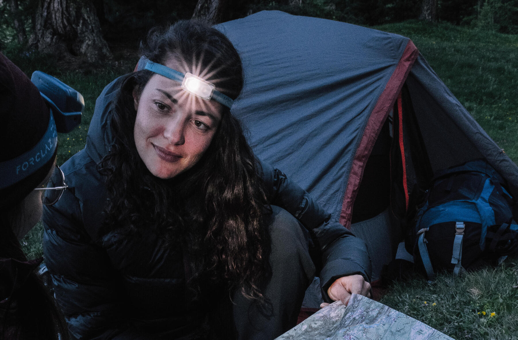 Woman camping and wearing a headlamp