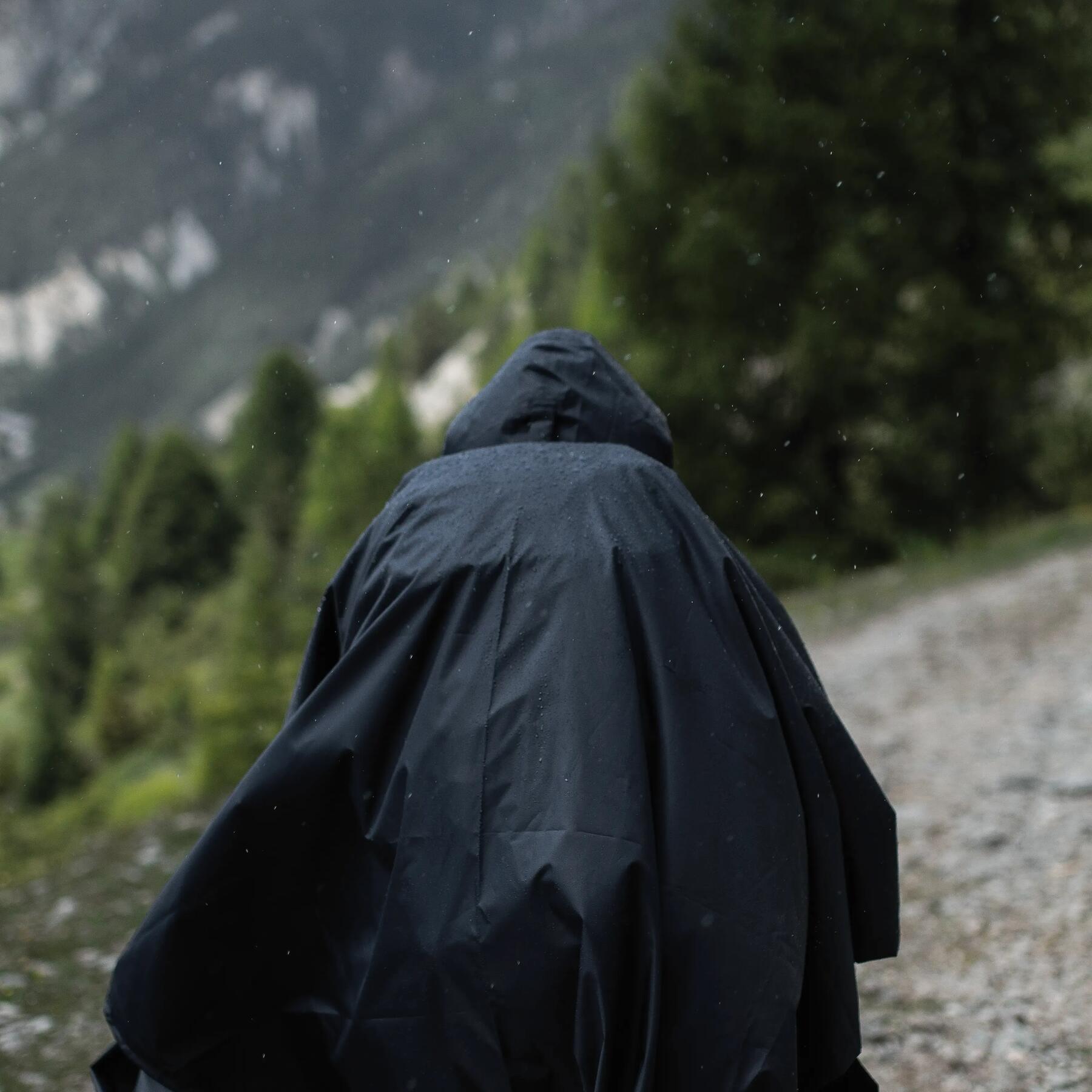 Kobieta chodząca po górach  podczas deszczowej pogody w nieprzemakalnej pelerynie