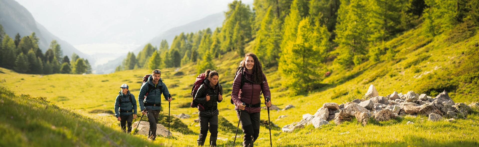osoby w odzieży trekkingowej z plecakami na plecach wędrują po górach